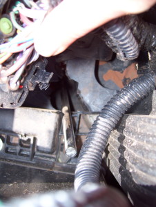 Broken shock piston rod sticking up through fuse box area in the engine compartment. (Looking down on the engine.)